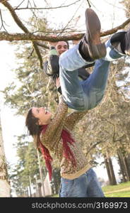 Twenty Something Female Helping Her Boyfriend Do A Pull Up In The Park