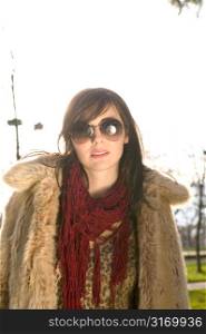 Twenty Something Female Wearing Sunglasses And A Fur Coat In A City Park