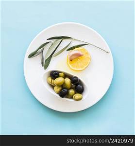 twig lemon slice garlic clove bowl olives plate blue background