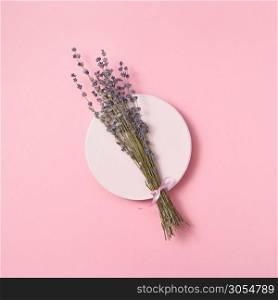 Twig of natural lavender on a round ceramic board on a pastel pink background with copy space. Holiday greeting card. Top view.. Organic lavender branch on a ceramic plate.