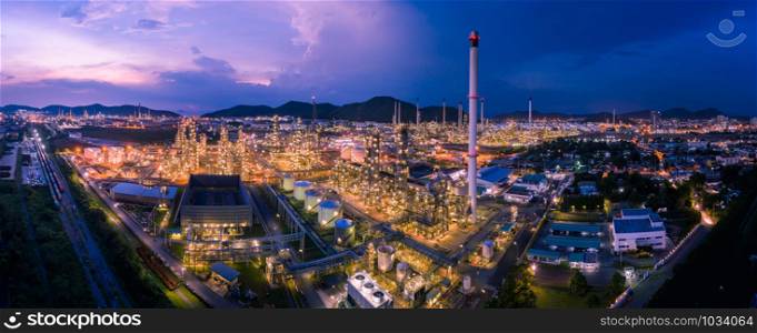 twilight cityscape panorama zone refinery industry factory and storage tank and container train railroad tracks at night and blue sky background aerial view thailand