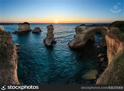 Twilight seascape with cliffs, rocky arch and stacks (faraglioni), at Torre Sant Andrea, Salento sea coast, Puglia, Italy