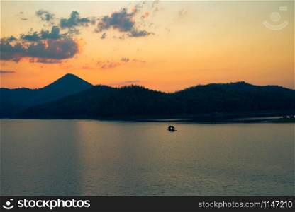 twilight sky river sunset yellow color landscape lake evening time clouds and mountains background / Fishing boat on the river