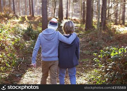 Twin brothers walking together in woods