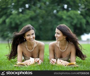 Twins young women reading a book outdoor