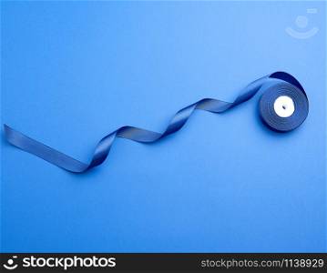 twisted dark blue silk ribbon on a blue background, element for the designer