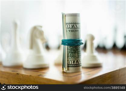 Twisted dollar bills standing on chess board in place of tower piece