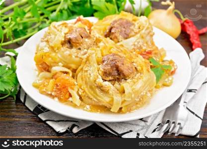 Twisted pasta with meatballs in the center with cream sauce, stewed tomatoes, bell peppers, onions and garlic in white plate on dark wooden board background