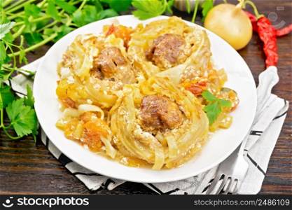 Twisted pasta with meatballs in the center with cream sauce, stewed tomatoes, peppers, onions and garlic in white plate on wooden board background
