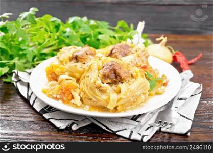 Twisted pasta with meatballs in the center with cream sauce, stewed tomatoes, peppers, onions and garlic in plate on napkin on wooden board background