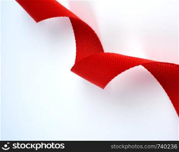 twisted red textile belt with a coarse fiber on a white background, close up