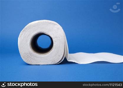 twisted roll of white paper towel on a blue background. Paper sheet. Household equipment. White napkin, close up