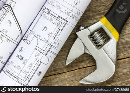 Twisted technical drawing and adjustable wrench on the wood background