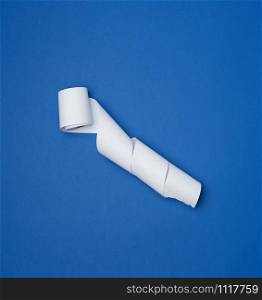 twisted white ribbon for cash register on a blue background, top view