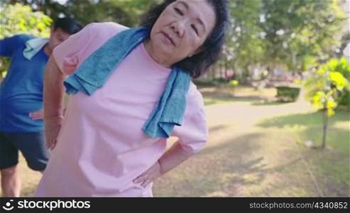 Two active Asian old aged people doing stretching warm up exercise inside public park, waist hip bending flexibility, healthy retirement life, family spending time together for outdoor activities