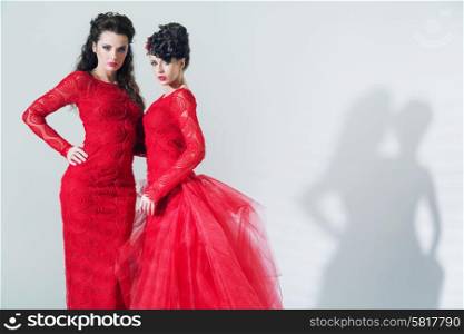 Two adorable brunette girlfriends wearing red dresses