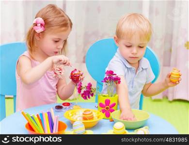 Two adorable children paint Easter eggs in kindergarten, drawing lessons, colorful decorations, traditional Eastertime art