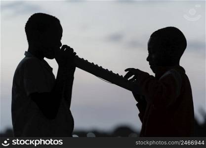 two african children sunset playing instrument