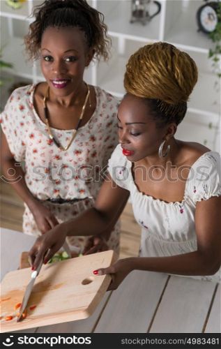 Two african women cooking in kitchen making healthy food salad with vegetables. Top view