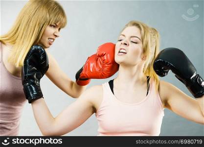 Two agressive women wearing boxing gloves having argue fight being mad at each other. Female violance concept.. Two agressive women having boxing fight