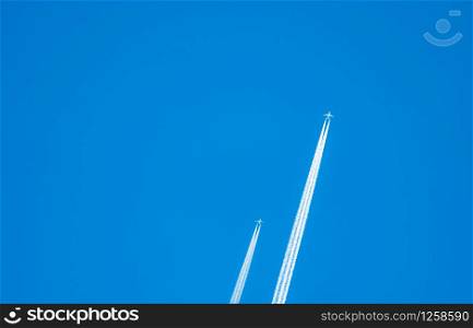 Two airplane with white condensation tracks. Jet plane on clear blue sky with vapor trail. Travel by aeroplane concept. Trails of exhaust gas from airplane engine. Aircraft with white stripes.