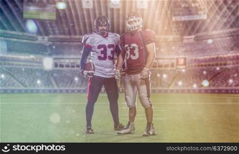Two American football players standing on the field of big modern stadium with flares and lights