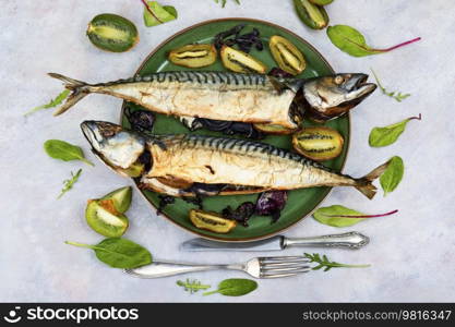 Two appetizing mackerel fish baked with kiwi pieces. Top view. Delicious smoked mackerel fish, seafood