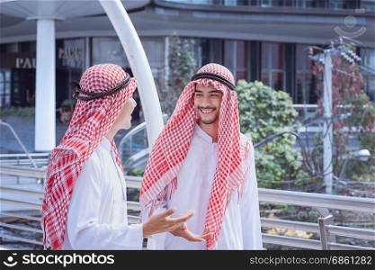 two arabian business men discuss and walk together around modern city