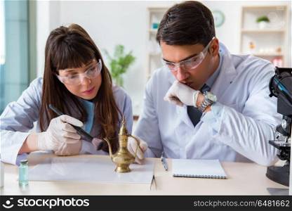 Two archeologists looking at ancient gold lamp