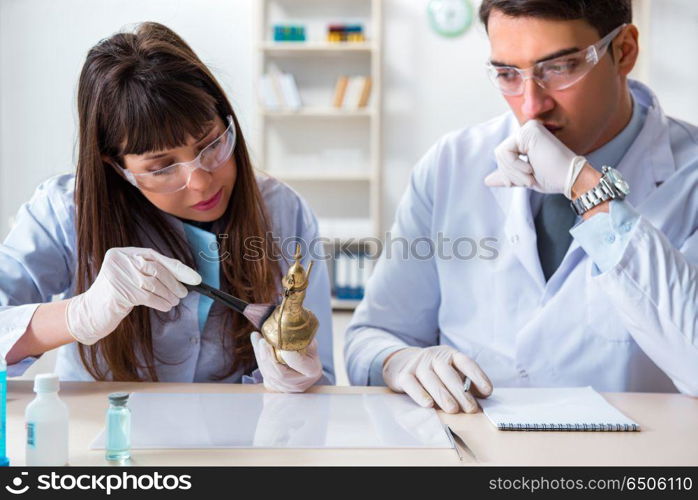 Two archeologists looking at ancient gold lamp