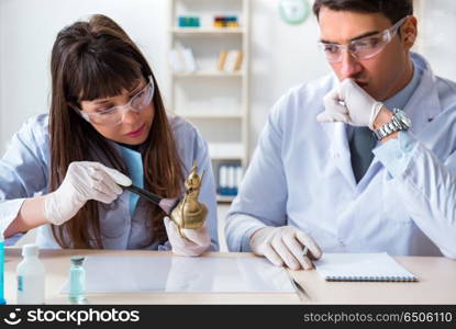 Two archeologists looking at ancient gold lamp