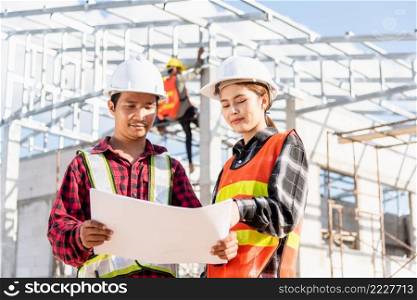 Two architect and client discussing help create plan with blueprint home building at construction site. Asian engineer foreman worker man and woman meeting talking on drawing paper project