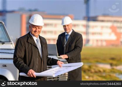 Two architect developers reviewing building plans at construction site