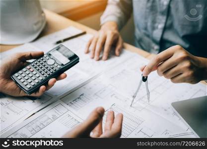 Two architect working at construction site and compass drawing pointing on blueprint with calculator calculate.