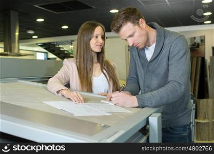 two architects at desk in office drawing building plans