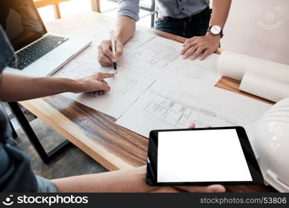 Two Architects engineer discussing data working and tablet, laptop with blueprint - Closeup on hands and project print.