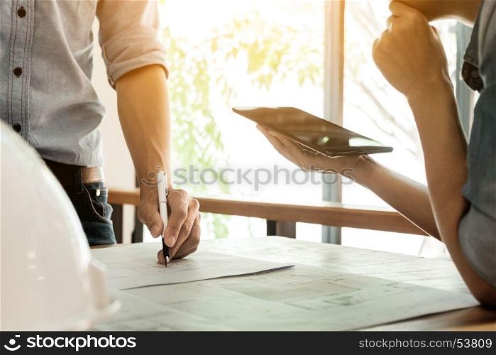 Two Architects engineer discussing data working and tablet, laptop with blueprint - Closeup on hands and project print.