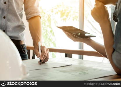 Two Architects engineer discussing data working and tablet, laptop with blueprint - Closeup on hands and project print.