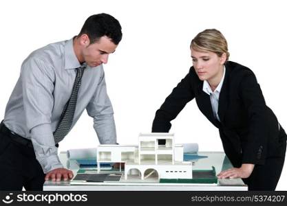 Two architects examining scale model of housing