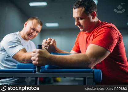 Two arm wrestlers fighting on their hands at the table with pins, battle in action, wrestling competition. Wrestle challenge, power sport