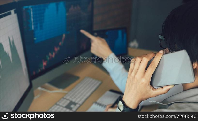 Two asian agent man working and analysis together in office market financial charts and graphs and calling to customer.