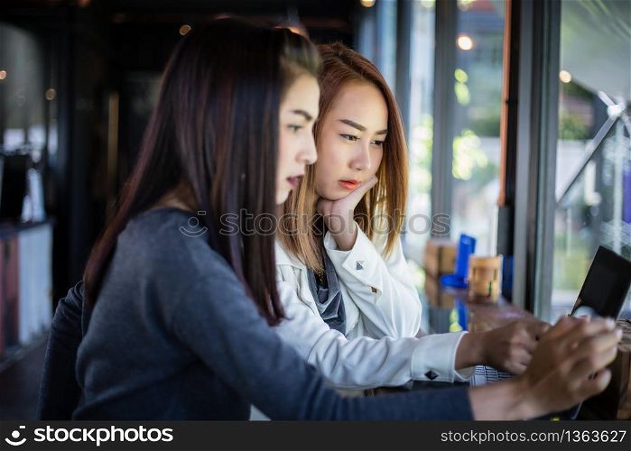 Two Asian business women using notebook working and Discussion of the important contract at coffee shop