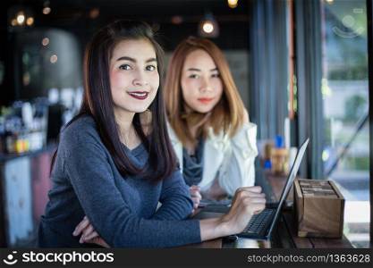 Two Asian business women using notebook working and Discussion of the important contract at coffee shop