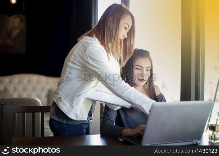 Two Asian business women using notebook working and Discussion of the important contract at office ,soft focus