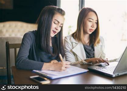 Two Asian business women using notebook working and Discussion of the important contract at office ,soft focus