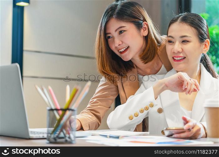 Two asian businesswomen working with the partner business via technology laptop in modern meeting room, office or working space, coffee break, partner and colleague concept