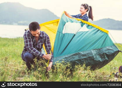 Two Asian couples prepare pitch camping tent to stay outdoors meadow overnight for honeymoon camping picnic. People lifestyle and Valentine day love concept. Nature travel vacation relaxation activity