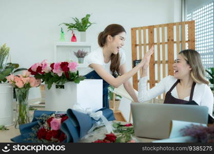 Two asian female florist working at flower shop with laptop.