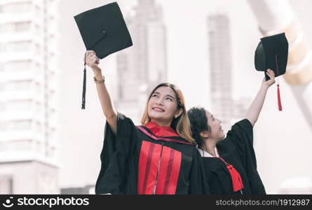 Two asian female students wearing uniform, cap and smiling with happiness after graduation. Education Concept.