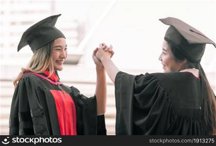 Two asian female students wearing uniform, cap and smiling with happiness after graduation. Education Concept.